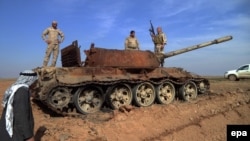 Iraqi soldiers stand on a damaged tank during fighting against IS militants near Tikrit on February 24.