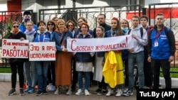 Journalists from the Belarusian Tut.by media outlet hold banners reading "I don't protest but work" (left), "This is me at work" (center), and "Freedom for journalists!" as they stand in front of a police station in Minsk in September 2020. They were protesting the arrest of colleagues who were covering anti-government protests at the time. Tut.by's news website has since been blocked by Belarusian authorities. 