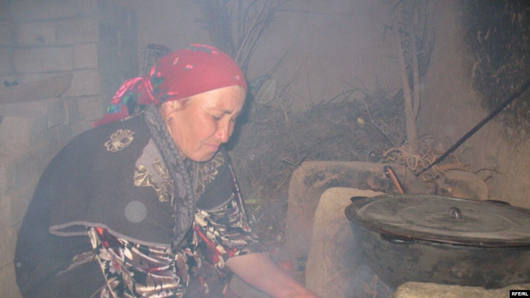 A Tajik woman cooks food over an open fire due to lack of electricity.