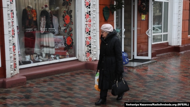 Перехожа розглядає вітрину магазину з національним вбранням в центрі Дніпра