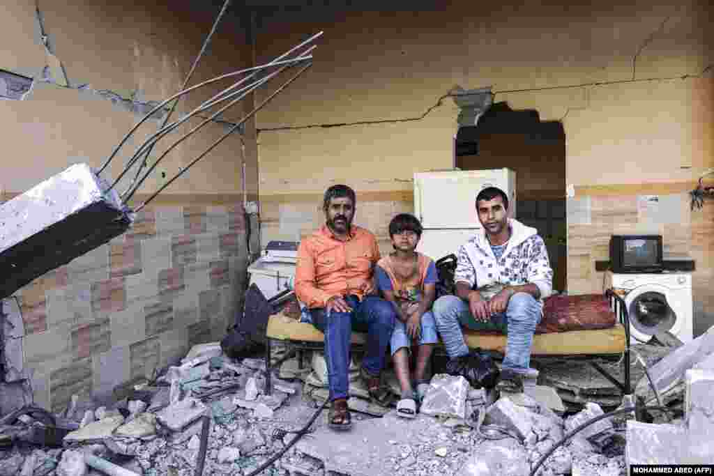 Мансур Абу Гадин (слева) и два его сына Мустафа и Мохамед (справа) позируют для фотографии возле своего разрушенного дома в городе Газа 27 мая 2021 года, после конфликта между Израилем и движением &laquo;Хамас&raquo;, базирующемся в Секторе Газа