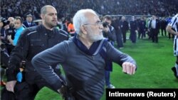 Russian-born Greek businessman and owner of PAOK Salonika, Ivan Savvides (center) takes the field , pictured with what appears to be a gun in his holster during his soccer team's game with rivals AEK Athens on March 11. 