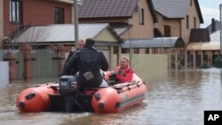 A woman and her pet are evacuated from a flooded street ride in the Russian city of Orenburg earlier this week. 