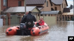 A woman and her pet are evacuated from a flooded street ride in the Russian city of Orenburg earlier this week. 