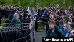 Demonstrators (right) stand outside a fence blocked by police as they protest plans to construct a church in a park in Yekaterinburg on May 14.