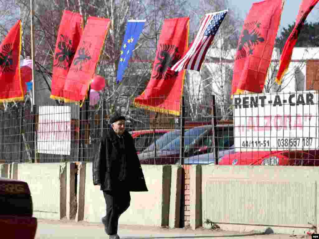 Në Prishtinë - Caption: epa01256135 Ethnic Albanian passes near Albanian, US and EU flags in Pristina, Kosovo, 15 February 2008.