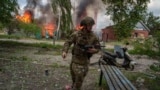 A police officer runs past a burning house destroyed by a Russian air strike in Vovchansk on May 11.