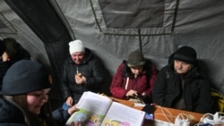 Жители Киева в одном из специально оборудованных пунктов, где можно обогреться, зарядить телефон и попить чаю