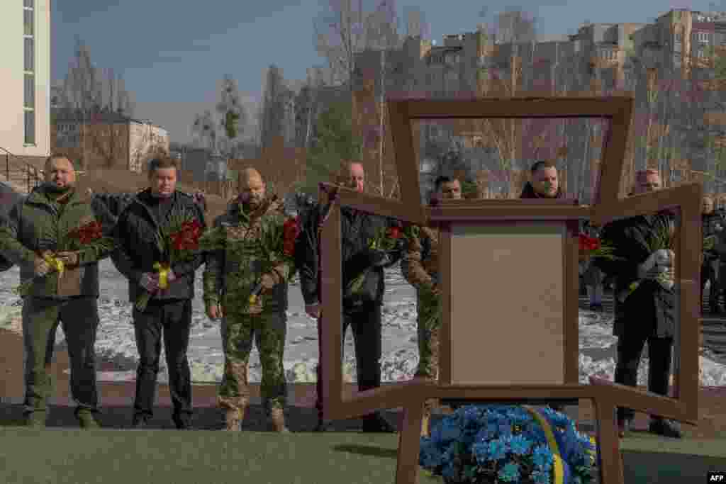 Ukrainian soldiers and others gather at a mass grave memorial on February 24 during a commemorative event in Bucha for those who died in a Russian massacre in the town northwest of Kyiv three years ago. 