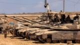 Israeli army soldiers stand atop main battle tanks deployed at a position along the border with the Gaza Strip and southern Israel on July 29, 2025.