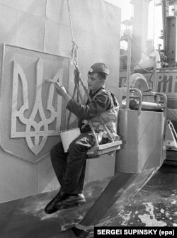 Marinar ucrainean care pictează emblema națională pe o navă din Sevastopol, 1993.