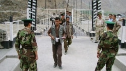 Таджикские пограничники проверяют документы людей, пересекающих таджикско-афганскую границу на мосту через реку Пяндж