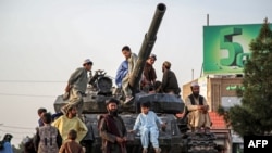 <p> Afghan men and children sit atop the remains of a Soviet-era tank on a square in Herat. 