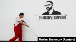 A cleaner mops the floor past an exhibit dedicated to Russian theater director Kirill Serebrennikov, who is accused of embezzling state funds and placed under house arrest, during a press preview of the Cosmoscow modern art fair in Moscow.