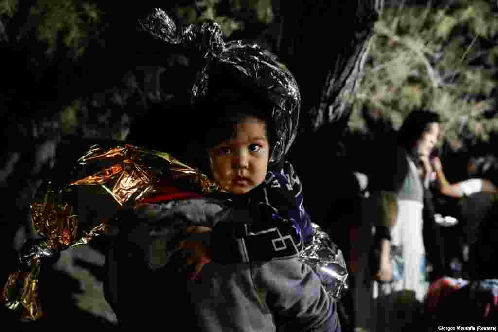 A man holds a child wrapped in a thermal blanket as migrants from Afghanistan arrive on a dinghy on the island of Lesbos, Greece. (Reuters/Giorgos Moutafis)