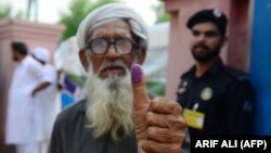 An elderly Pakistani man shows his inked thump outside a polling station after casting his vote in national elections in Lahore on July 25. 