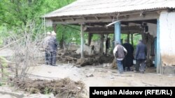 Residents of the village of Kulundu in the Batken region inspect a building damaged in the flooding on April 26.