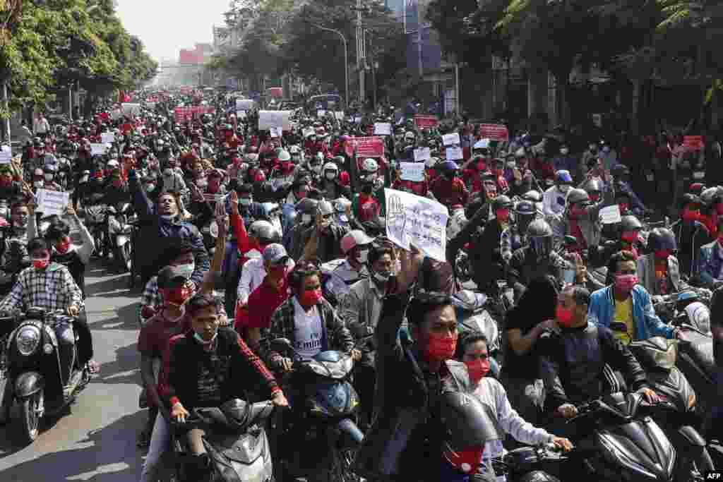 Protestatarii țin pancarte în timpul unei demonstrații ce are loc în apropierea palatului regal Mandalay