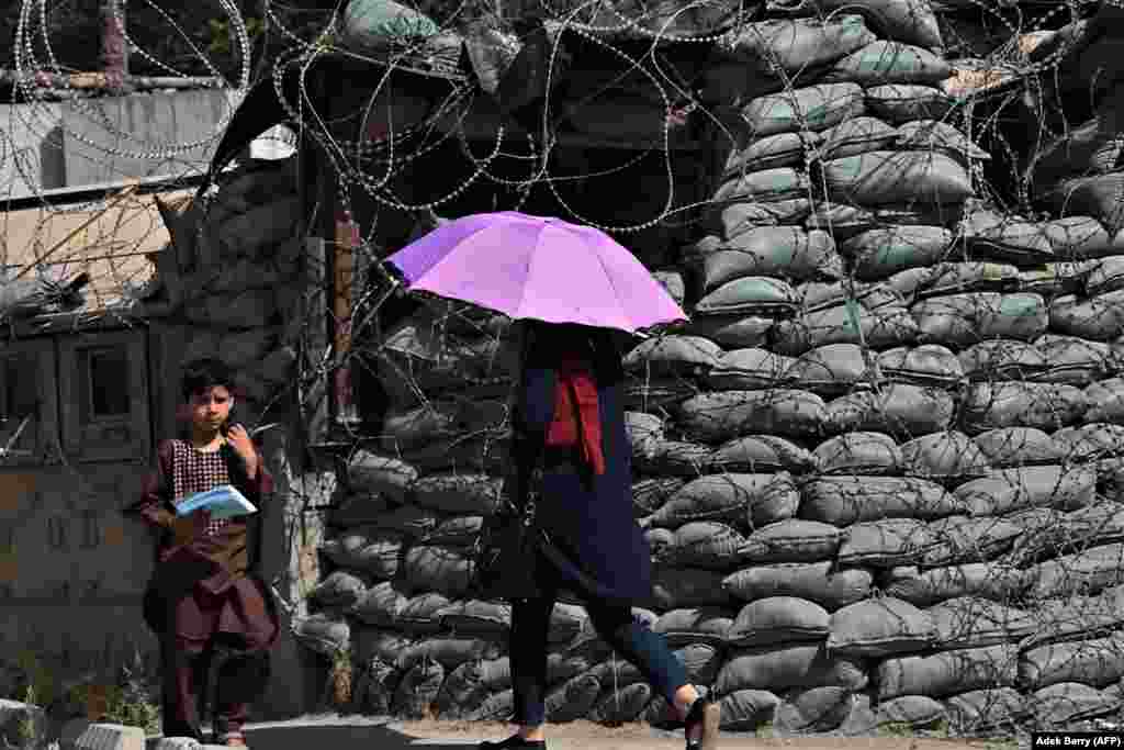 Ljudi prolaze pored sigurnosnog stupa prekrivenog bodljikavom žicom, Kabul.