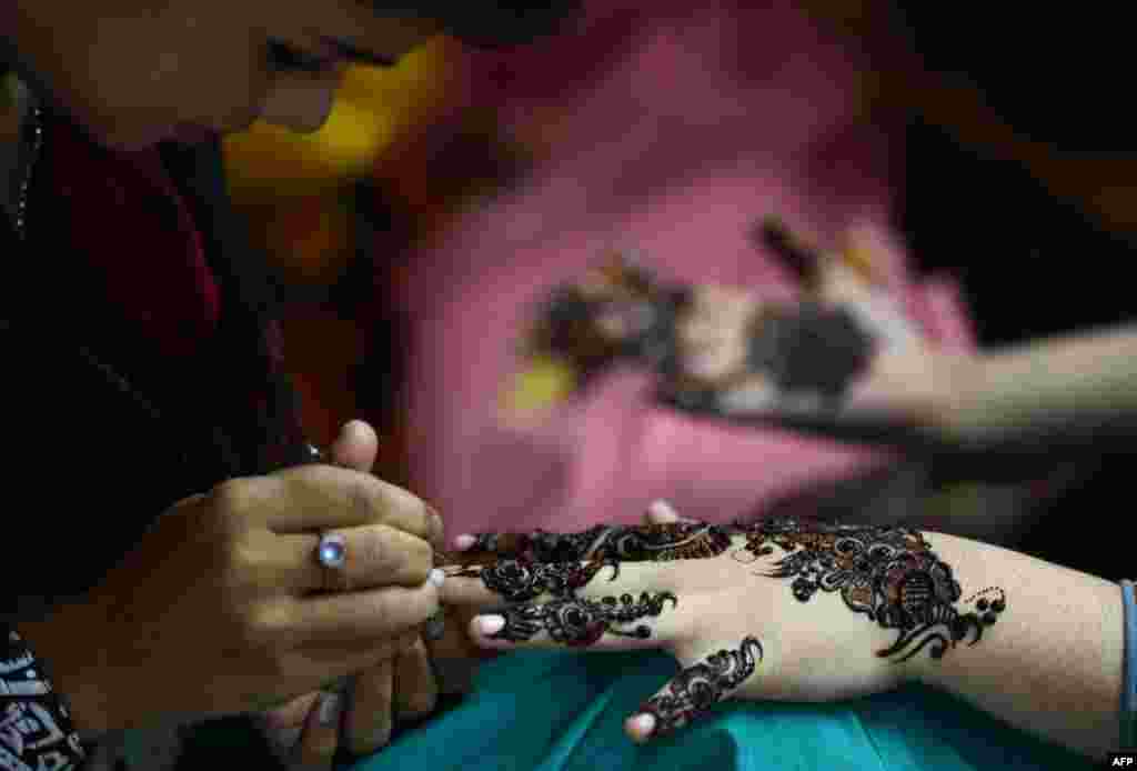 A beautician applies traditional henna designs to the hand of a customer ahead of the Muslim festivities of Eid al-Fitr in Karachi, Pakistan. (AFP/Asif Hassan)