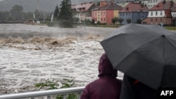 Oamenii urmăresc situația de pe un pod peste râul Biala, la Glucholazy, în sudul Poloniei, pe ploaie și vânt puternic. 