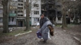 Жанчына нясе свае рэчы, каб эвакуавацца з Пакроўску Данецкай вобласьці. 12 красавіка 2025 году