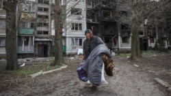 Жанчына нясе свае рэчы, каб эвакуавацца з Пакроўску Данецкай вобласьці. 12 красавіка 2025 году