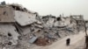 Syrians ride a motorcycle amid the destruction in a rebel-held neighborhood in Daraa, April 12, 2017