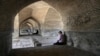 In this Tuesday, July 10, 2018 photo, people rest under an arch of the 400-year-old Si-o-seh Pol bridge, named for its 33 arches, that now spans a dried up Zayandeh Roud river, in Isfahan, Iran.