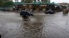 A motorcycle and cars drive through a flooded road caused by heavy rain in Peshawar on April 15.