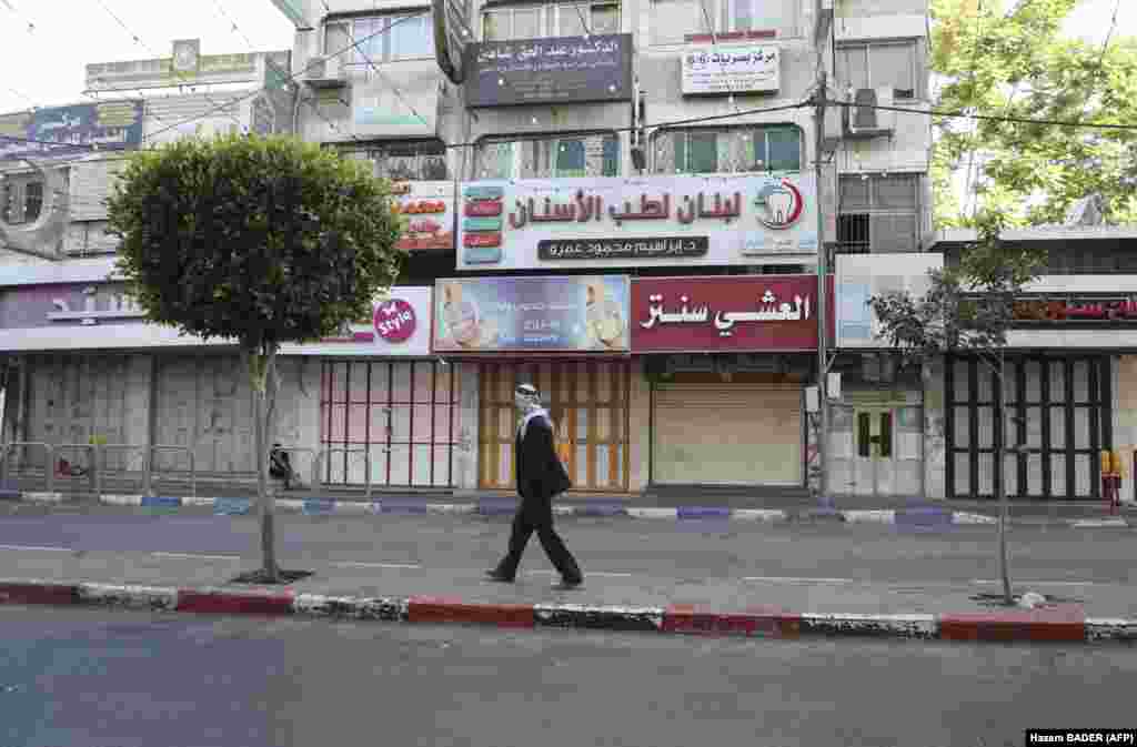 A man walks past shuttered Palestinian stores in Hebron city, as a general strike is observed in the occupied West Bank and Arab Israeli cities in solidarity with Gaza and Jerusalem, on May 18, 2021.