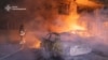 This handout picture taken and released by Ukrainian State Emergency Service on June 12, 2025 shows firefighters putting out burning vehicles parked outside a residential building destroyed during a Russian drone strike overnight in Kharkiv. 