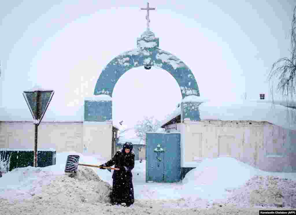 A nun shovels snowl in front of the gate of the Bogoslovsky nunnery in the village of Bogoslovo in the Vladimir region, some 190 kilometers outside Moscow, on February 4. (AFP/Konstantin Chalabov)