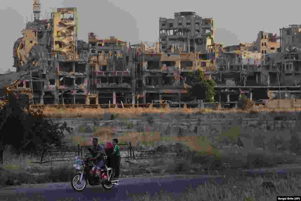 People ride a motorcycle past damaged buildings in the old town of Homs, Syria. (AP/Sergei Grits)