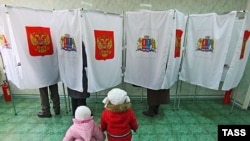 Children wait as their parents vote in ballot booths at a polling station in Ivanovo.