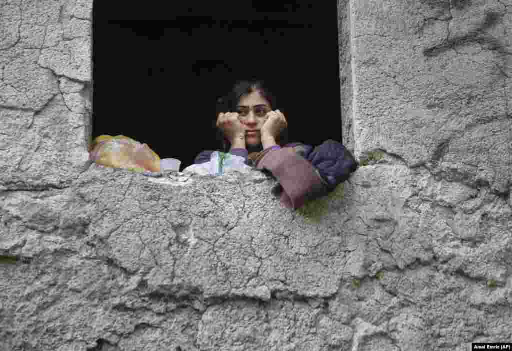 A migrant woman looks out of the window of a former hotel, now serving as a shelter, in the western Bosnian town of Bihac. (AP/Amel Emric)