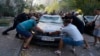 Emergency services and local residents move a damaged car after a Russian aerial bomb struck a multistory residential building in Kharkiv on September 15. 