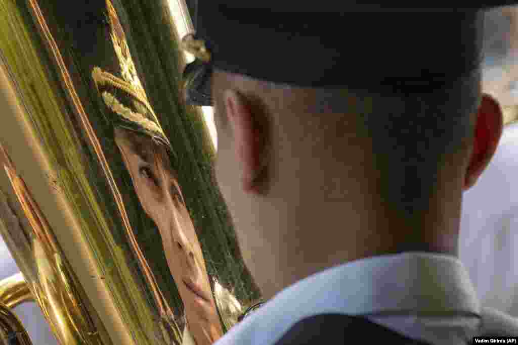 A member of a military band is reflected in a brass instrument during a ceremony in Bucharest marking Aviation Day, which celebrates aviators -- military and civilian -- who lost their lives in the line of duty or contributed to the evolution of Romanian aviation.