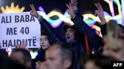 Протестиращ носи плакат с надпис "Али Баба и 40-те разбойници" по време на протеста срещу правителството в Тирана, 22 декември 2025 г.
