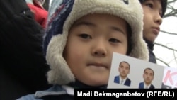 An Uzbek boy holds pictures of his father, who is in pretrial detention in Almaty, during a picket of Uzbek refugees' wifes against extradition to Uzbekistan in December.