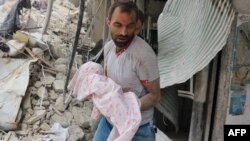 A Syrian man carries the body of an infant retrieved from under the rubble of a building following a reported air strike on the Al-Muasalat area in the northern Syrian city of Aleppo on September 23.