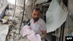 A Syrian man carries a dead baby retrieved from under the rubble of a building following an air strike on the Al-Muasalat area of Aleppo on September 23, 2016.