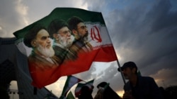 A man holds a flag featuring late leader of the Islamic Revolution Ayatollah Ruhollah Khomeini, late Supreme Leader of Iran Ayatollah Ali Khamenei, and Iran's new Supreme Leader Mojtaba Khamenei, at a rally in Tehran on April 29. 