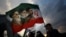 A man holds a flag featuring late leader of the Islamic Revolution Ayatollah Ruhollah Khomeini, late Supreme Leader of Iran Ayatollah Ali Khamenei, and Iran's new Supreme Leader Mojtaba Khamenei, at a rally in Tehran on April 29. 