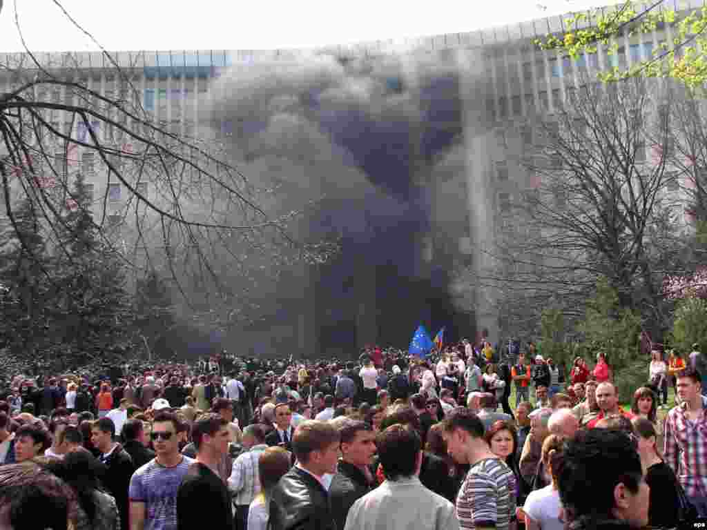 Caption: epa01690564 Young Moldovan protesters wave European Union (EU) flags and shout anti-communist slogans as smoke billows from a fire outside the parliament building in Chisinau, Moldova, 07 April 2009. Thousands of anti-communists protesters, most of them students, gathered to contest parliamentary elections results, asking for new elections. Although Moldova's ruling communist party gained enough votes to hold on to power in parliament on 05 April 2009, they lacked the number of seats to install a new president.