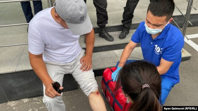 Медработник помогает активисту Ырысбеку Токтасыну, который получил ссадину в полицейском кольце. Алматы, 6 июля 2021 года