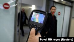 Almaty aeroportunda ýolagçylary ýylylygy görüji skanir bilen barlagdan geçirýärler. Illýustrasiýa suraty.