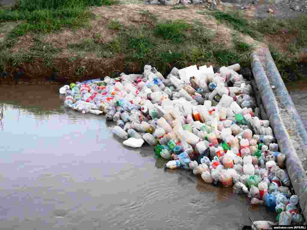 Akar suwuň kenaryna ýygnanan plastik çüýşeler