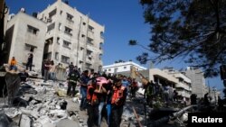 Punëtorët e shpëtimit mbajnë një viktimë mes rrënojave në vendin e sulmeve ajrore izraelite, në Gaza, 16 maj 2021. 