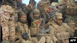 Shi'ite fighters flash the victory sign as they advance toward Mosul. 